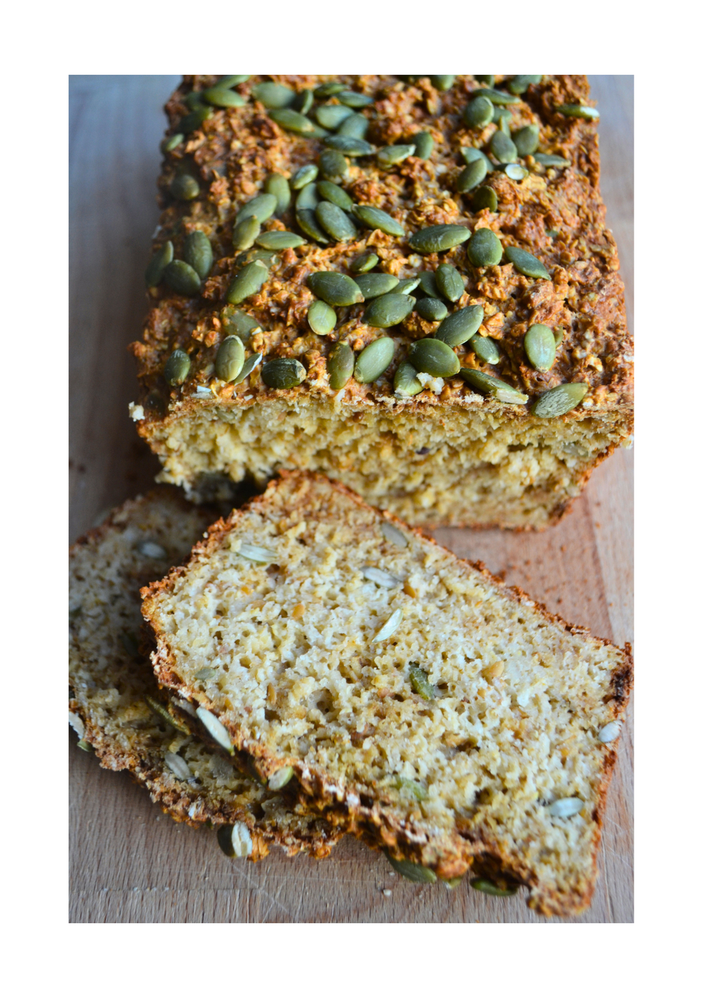 Loaf of bread with green seeds on a wooden cutting board