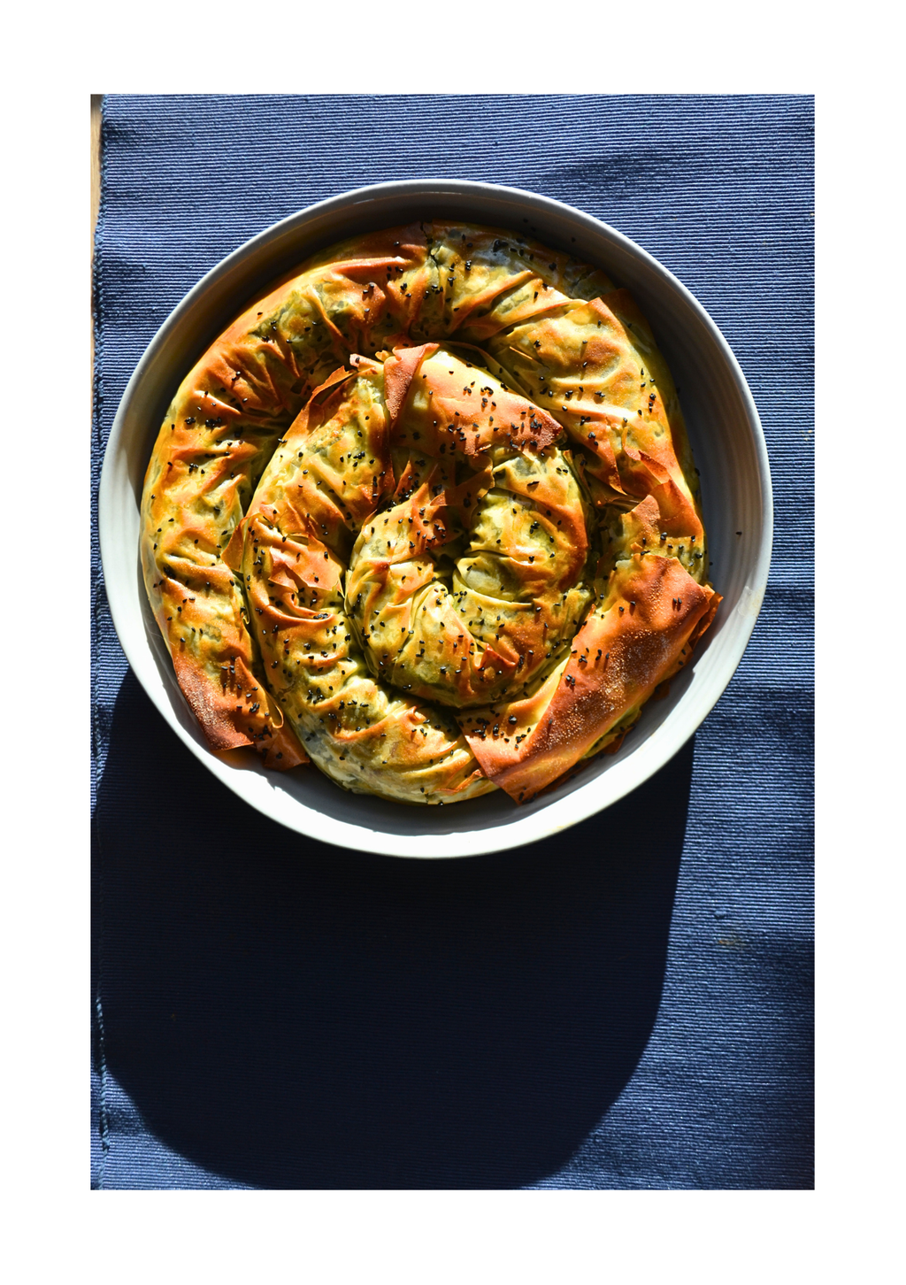 Baked dish in a spiral shape on a white plate with a blue background